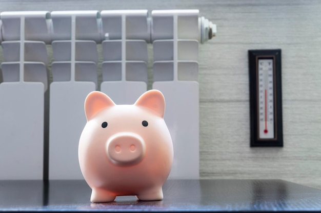 Piggy bank with thermometer near heating radiator price heating