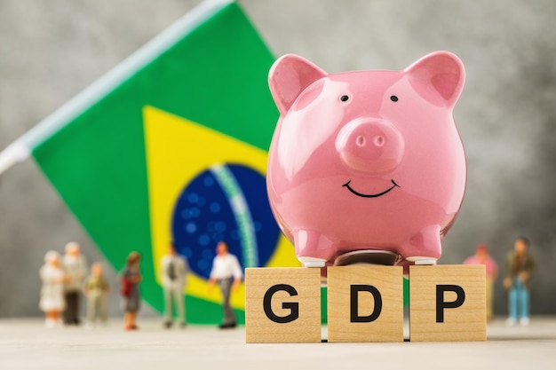 Piggy bank wooden cubes with text flag and plastic toy men concept on the theme of Brazilian GDP