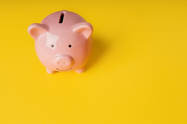 Photo piggy bank on a yellow background with copy space