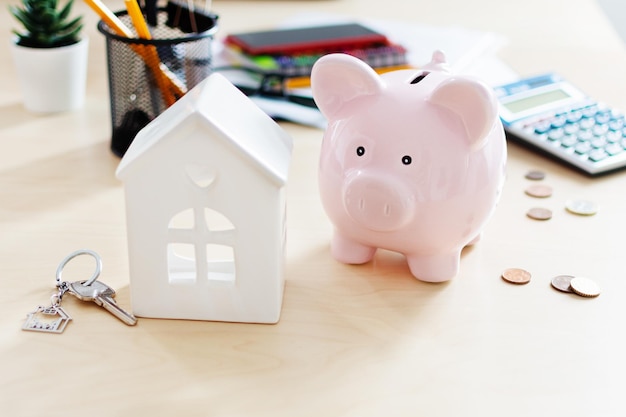 Foto calcolatrice salvadanaio e modello di casa su bianco risparmio per l'acquisto del concetto di casa