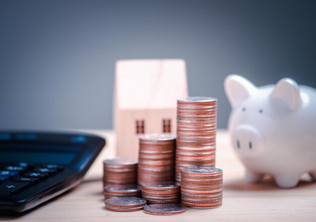 Piggy coin bank calculator and house model on wooden background savings for buying house concept real estate market