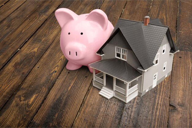 Piggybank and house model on wooden background