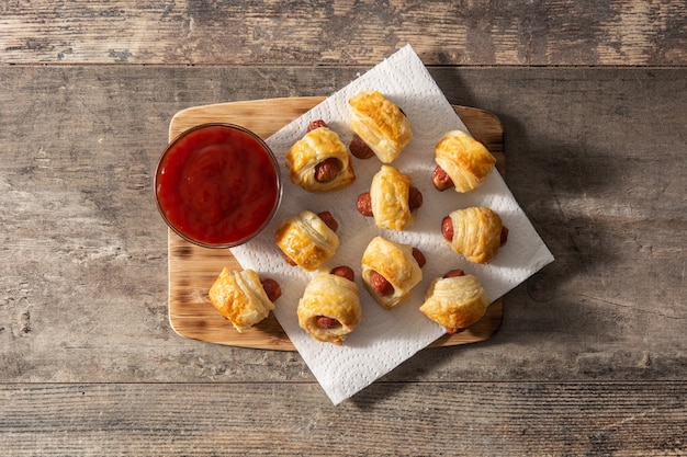 Pigs in blankets. Mini sausages wrapped in puff pastry with ketchup sauce.