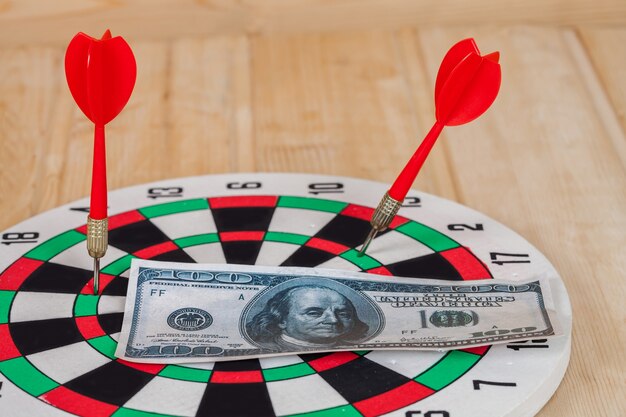 Foto pijltjepijl die in bullseye op dartboard met geld raakt