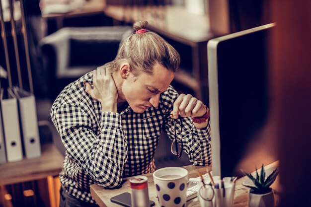 Foto pijn in de nek. negatieve opgetogen man buigt hoofd en raakt zijn nek aan