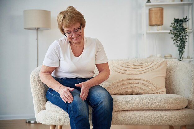 Pijn in het been Senior oudere vrouw is thuis in de woonkamer