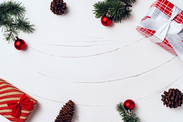 Pijnboom versierd met kerstballen en verpakte kerstcadeaus op witte houten achtergrond bovenaanzicht