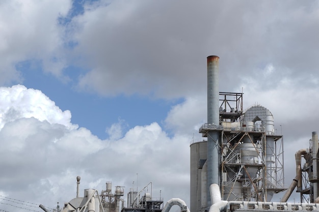 Pijp van de cementfabriek tegen humeurige lucht Productielocatie industriële werkruimte