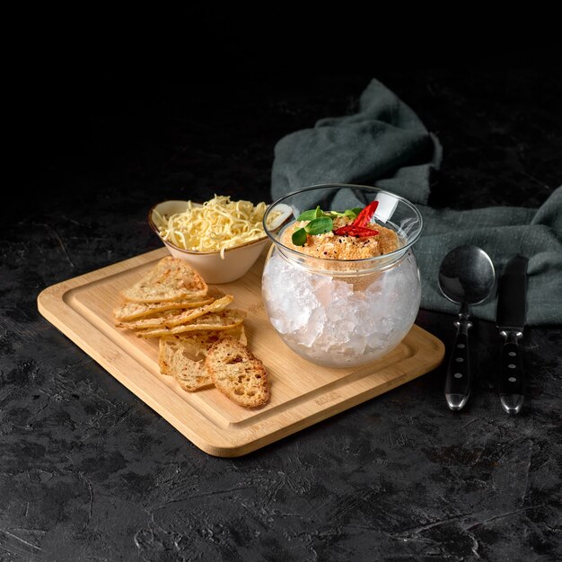 Caviale di luccio, su ghiaccio, con crostini di pane e burro, su un piatto trasparente, su fondo scuro