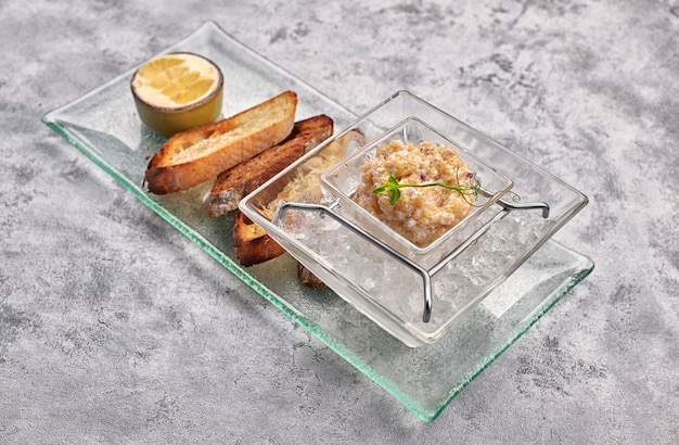 Pike fish caviar, on ice, with croutons and butter, on a transparent dish, on a white background