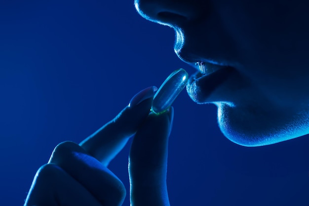 pil of medicijn in de hand in de buurt van de mond in ultraviolet licht