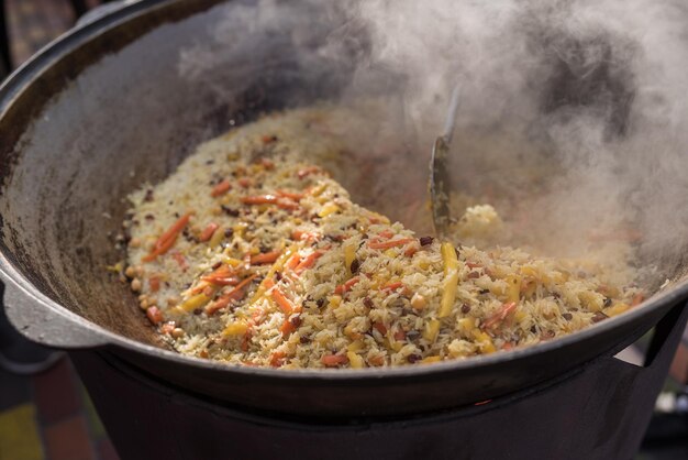 Pilaf koken in een grote ketel op straat Aziatische keuken