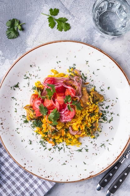 Pilaf with meat,  tomatoes and onions. Uzbek food on a plate. Top view