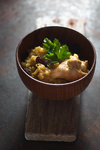 Pilaf with rice chicken and raisins in a wooden bowl