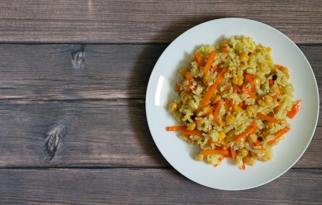 Pilaf with rice chickpeas and spices on wooden background with copy space