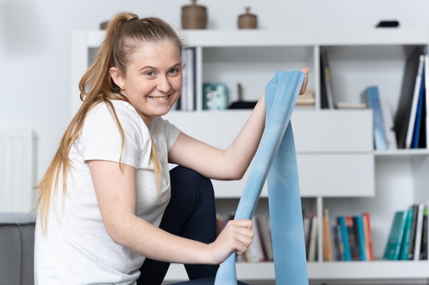 Pilates teacher looking at camera and showing a rubber\
band