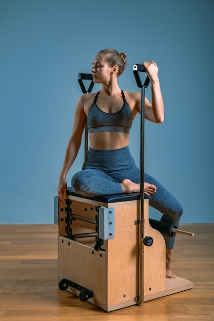 Pilates vrouw in een hervormer die rekoefeningen doet in de sportschool. Fitnessconcept, speciale fitnessapparatuur, gezonde levensstijl, plastic. Kopieer ruimte, sportbanner voor reclame.