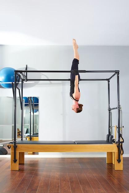 Pilates woman in cadillac acrobatic upside down