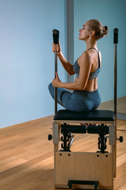 Pilates woman in a reformer doing stretching exercises in the gym. Fitness concept, special fitness equipment, healthy lifestyle, plastic. Copy space, sport banner for advertising