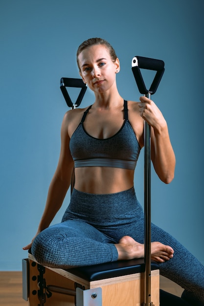 Pilates woman in a reformer doing stretching exercises in the gym. Fitness concept, special fitness equipment, healthy lifestyle, plastic. Copy space, sport banner for advertising.