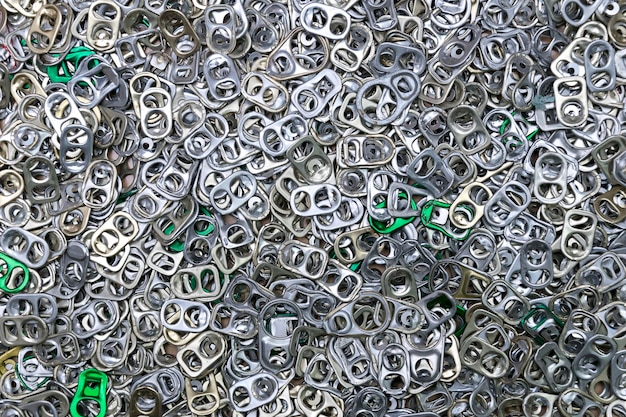 Photo a pile of aluminum hand pull tab good idea for environmental savingdonations for prosthetic legring pull tab aluminum pop tops of cans for background