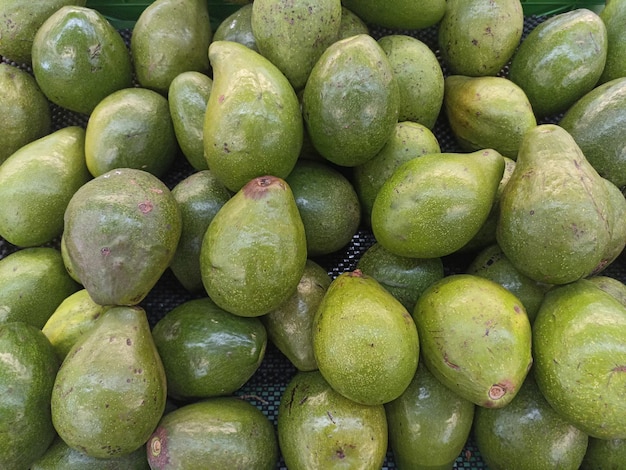 A pile of avocados are stacked on a table.