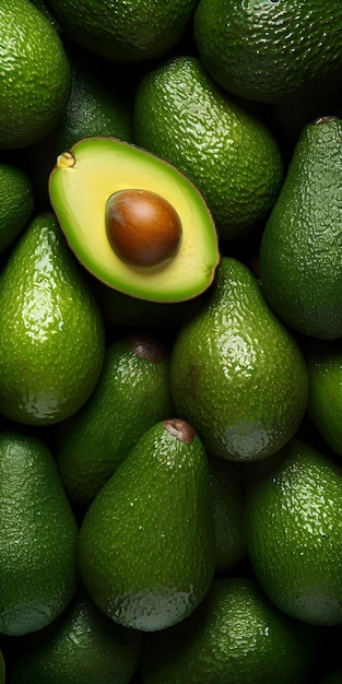 A pile of avocados with one of the avocados being cut in half.