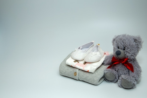 A pile of baby clothes and accessories with teddy bear