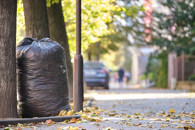 Pile of black garbage bags full of litter left for pick up on street side. Trash disposal concept.