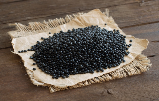 Pile of Black Lentils on wood, close up