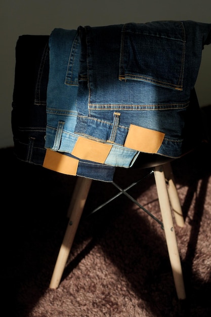 A pile of blue jeans on a chair