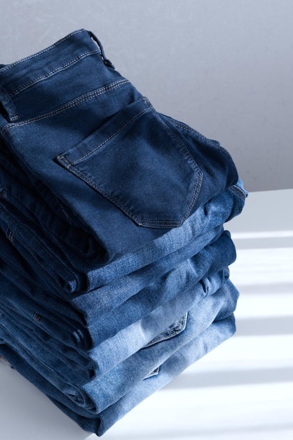 A pile of blue jeans on a light background close up sunlight diagonal