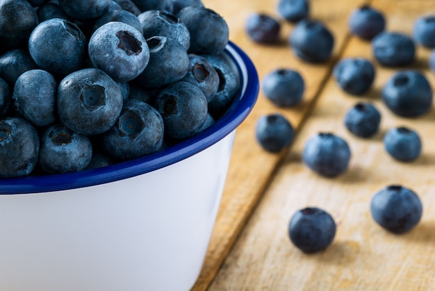 Pile of blueberries in the bowl on table close up background