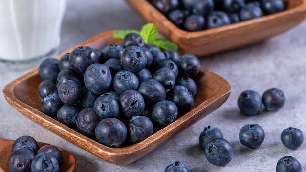 Pile of blueberry fruit in a bowl plate on a tray over gray cement concrete background close up healthy eating design concept