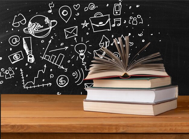 Pile of books on table on chalkboard background