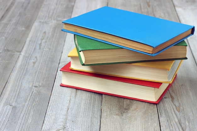 Pile of books with color covers on a wooden table. 