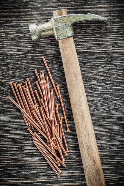 Pile of brass nails claw hammer on wooden board