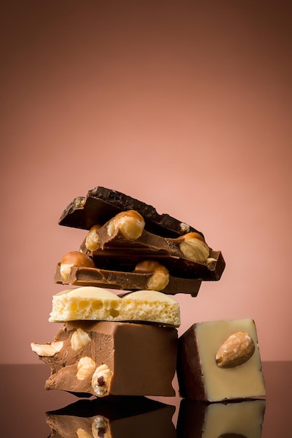 Pile of broken chocolate on table against brown studio background