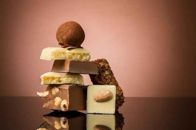 Pile of broken chocolate on table against brown studio background