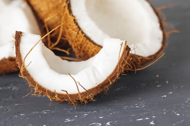 Mucchio delle noci di cocco rotte su fondo grigio strappato