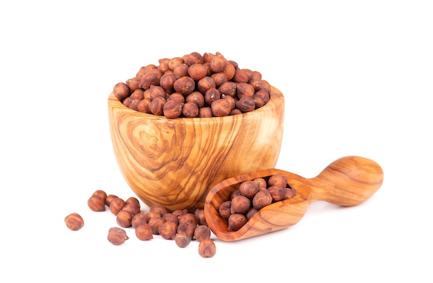 Pile of brown chickpeas in olive bowl and scoop, isolated on white background. Brown chickpea. Garbanzo, bengal gram or chick pea bean.