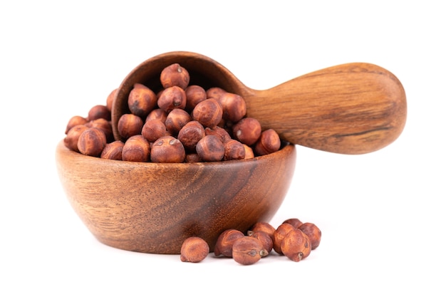 Pile of brown chickpeas in wooden bowl and spoon, isolated on white background. Brown chickpea. Garbanzo, bengal gram or chick pea bean.