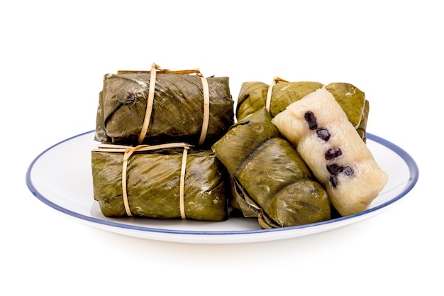 Pile of bundled boiled rice is stacked isolated on white background Thai dessert made with glutinous rice and coconut milk put banana filling wrapped in banana leaves and steamed until cooked