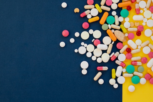 Pile of capsules, pills on a blue and yellow background