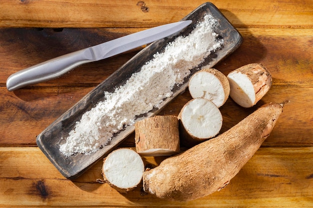 Photo pile of cassava cassava and cassava flour on a background of rustic wood manihot esculenta