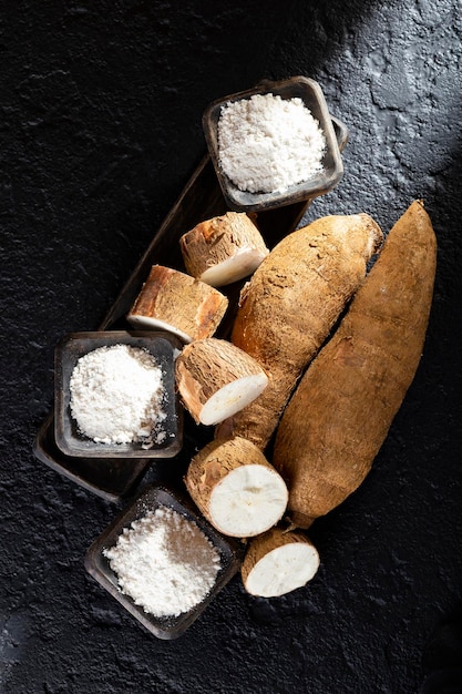 Pile of cassava and cassava flour on dark background Manihot esculenta