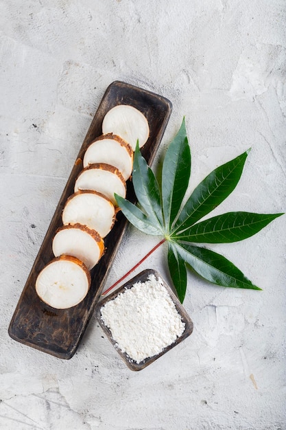 Pile of cassava root and cassava flour on a gray and white textured background Manihot esculenta