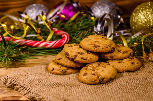 Pile of the chocolate chip cookies on sackcloth in front of christmas decorations