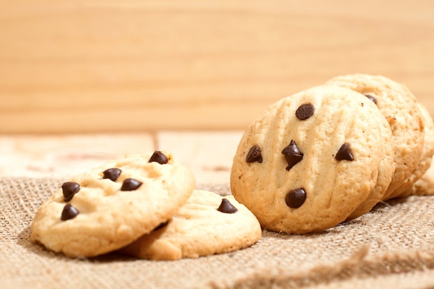 Pile of chocolate chip cookies on wooden table.