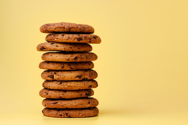 Pile of chocolate chip cookies on yellow background